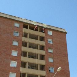 Edificio de varias plantas con trabajadores sujetados con arnés